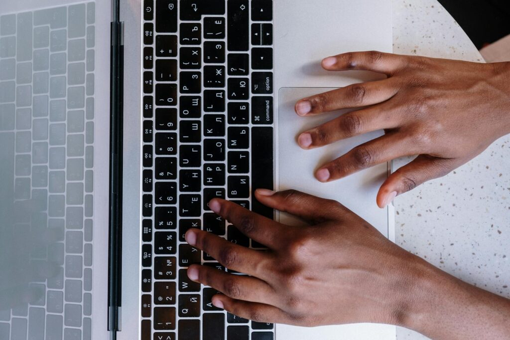 Hands typing on a laptop keyboard, showcasing online work and technology.