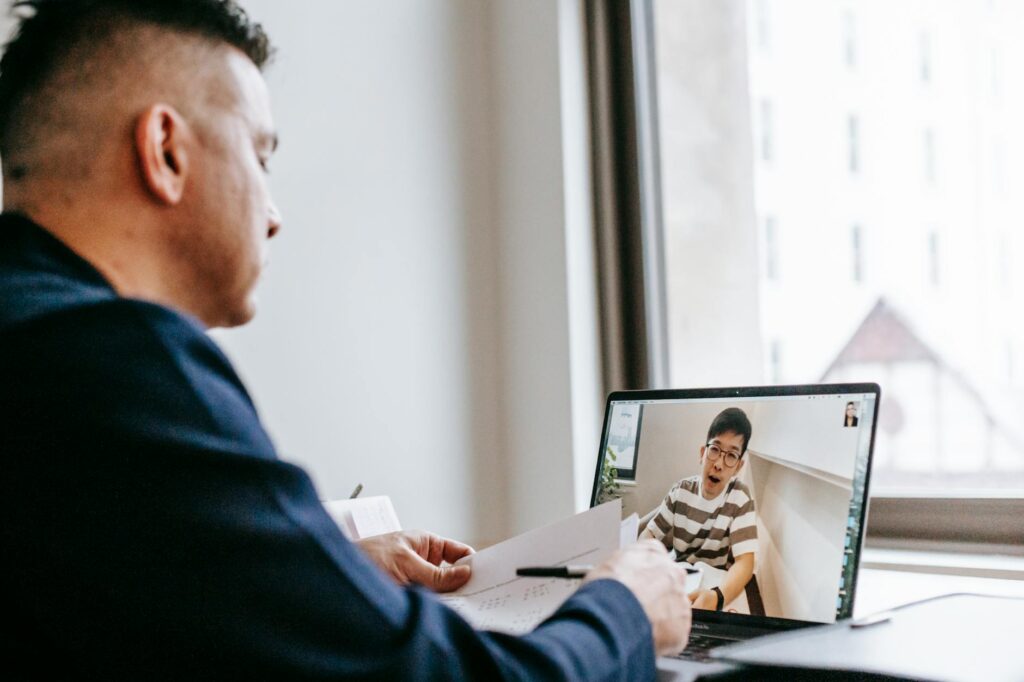 A professional discussing work over a video call using a laptop indoors.