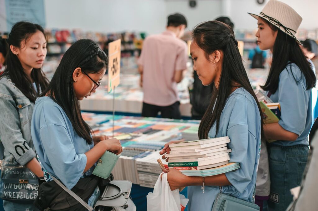 Students browsing and buying books in a busy bookstore environment.