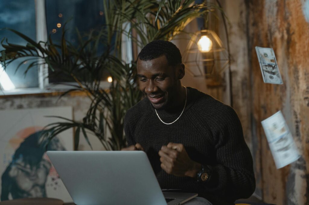 Excited man at home office celebrating success during an online meeting. Perfect work from home setup.