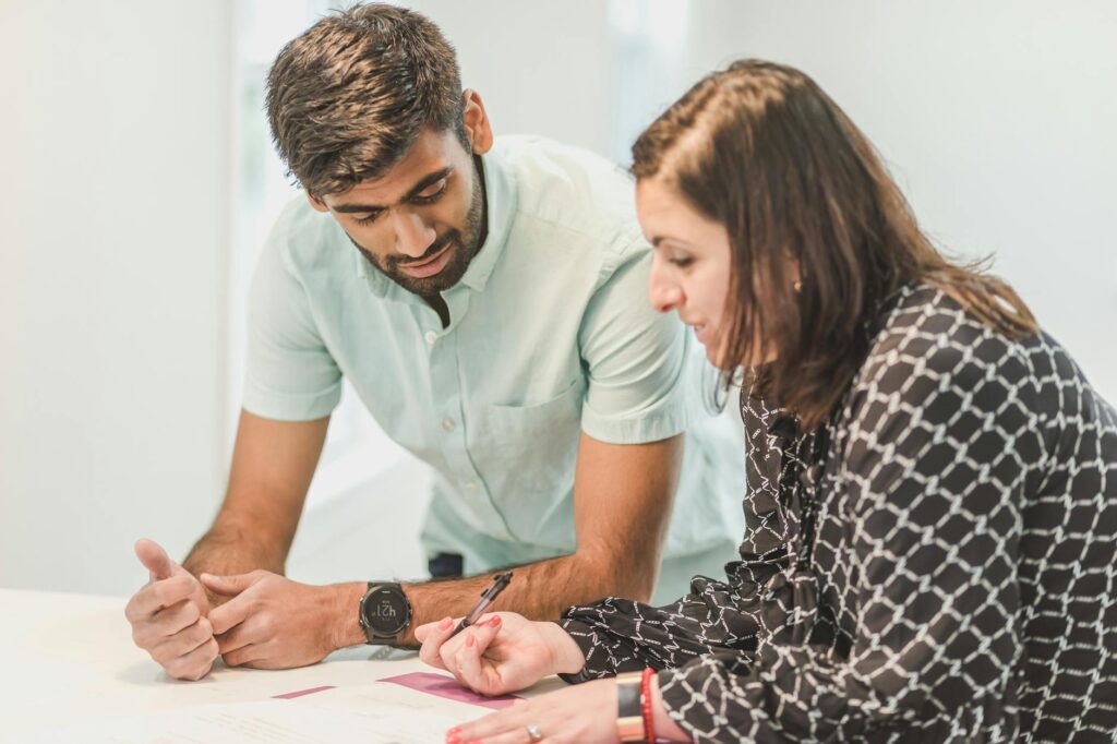 A real estate agent assists a client with home buying paperwork indoors.