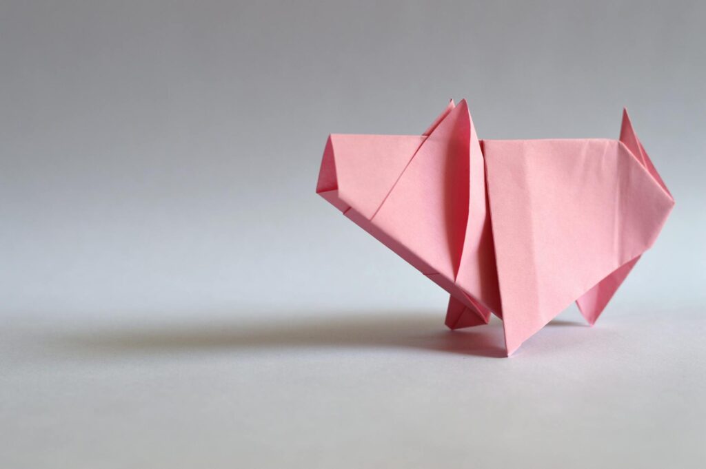 A pink paper origami pig, showcasing traditional Japanese folding art.
