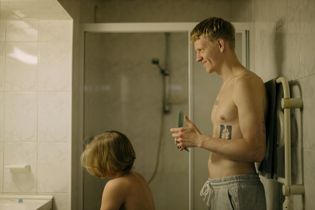 Man giving a haircut to a family member in an intimate bathroom setting.